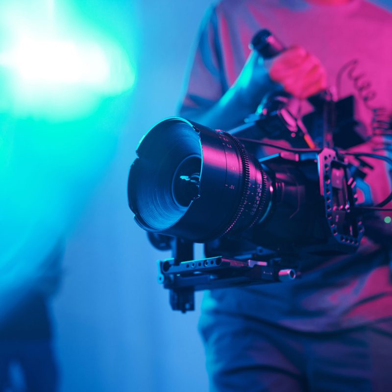 Close-up of young cameraman shooting with professional camera while making content in studio