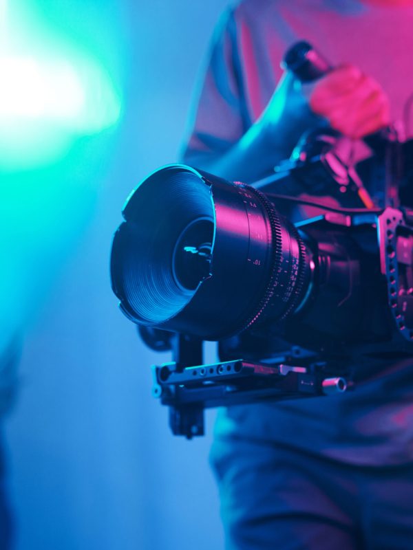 Close-up of young cameraman shooting with professional camera while making content in studio