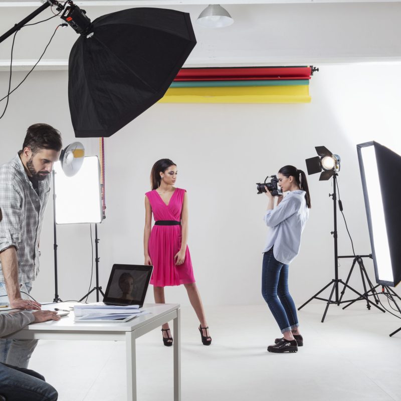 Photographer photographing fashion model in white backdrop photography studio shoot
